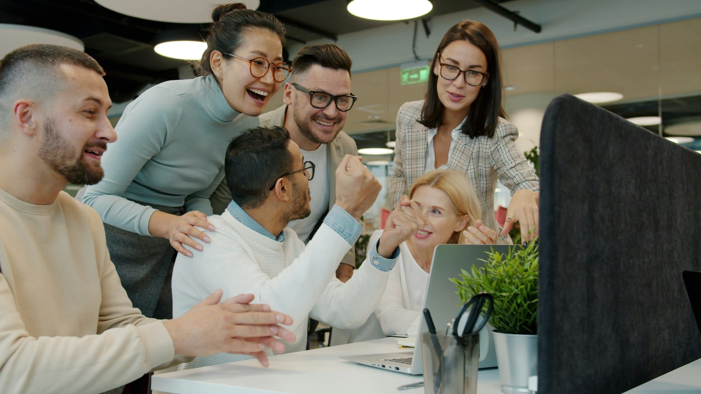 A team gathered around a desk, cheering.